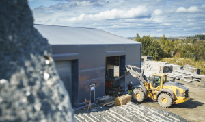 Rubbhall og stor traktor som frakter stein inn i hallen